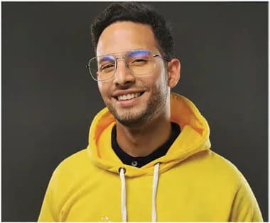 Tony sonriendo, con gafas y sudadera amarilla